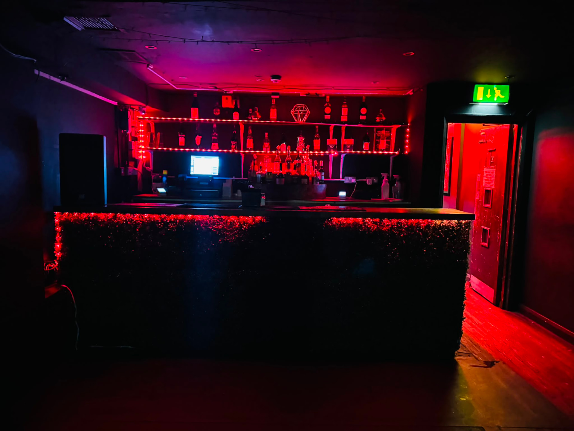 Back bar counter framed by red fairy lights and backlit spirit bottles