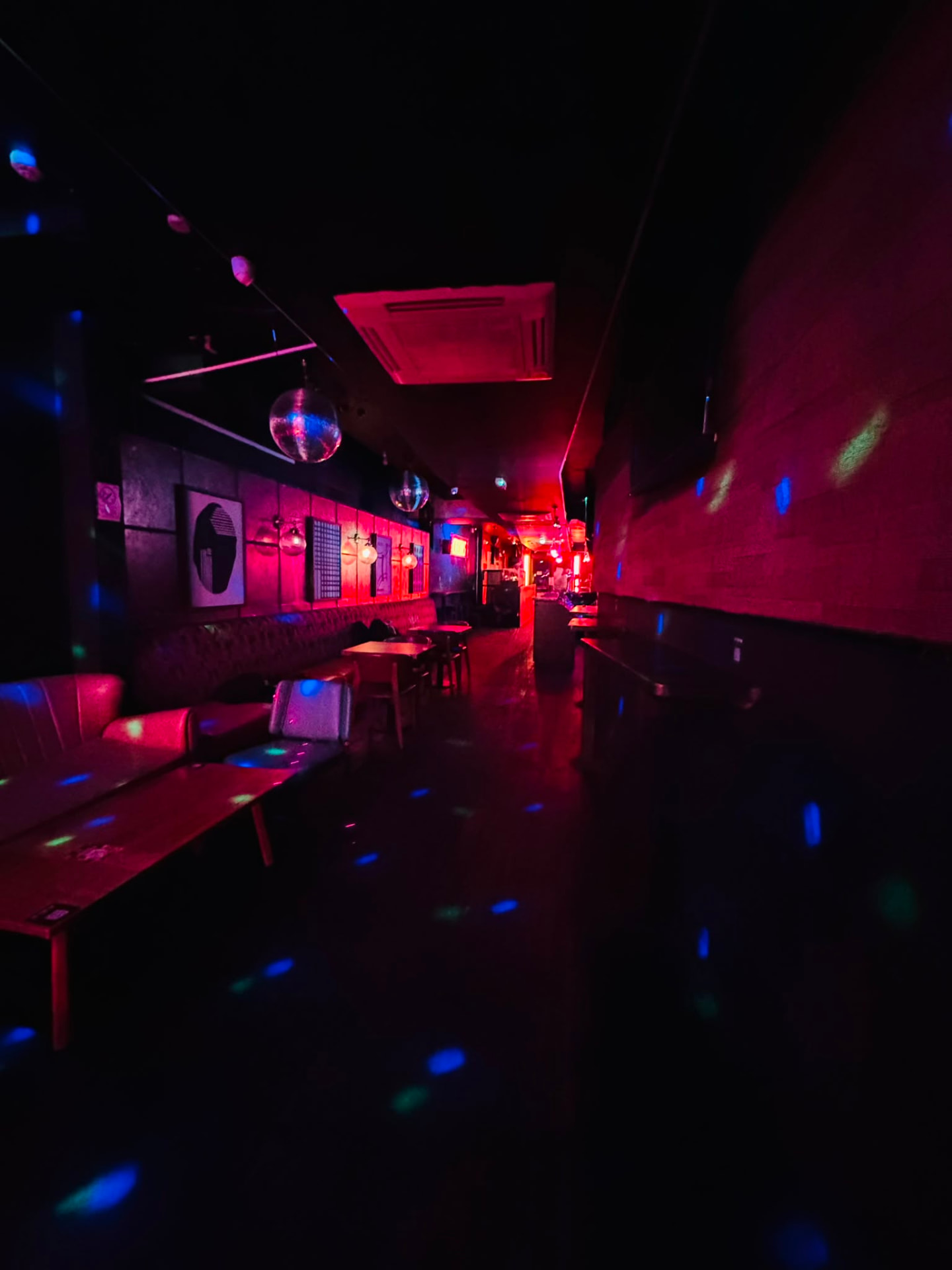 Booth seating and disco balls scattering blue light across the club floor