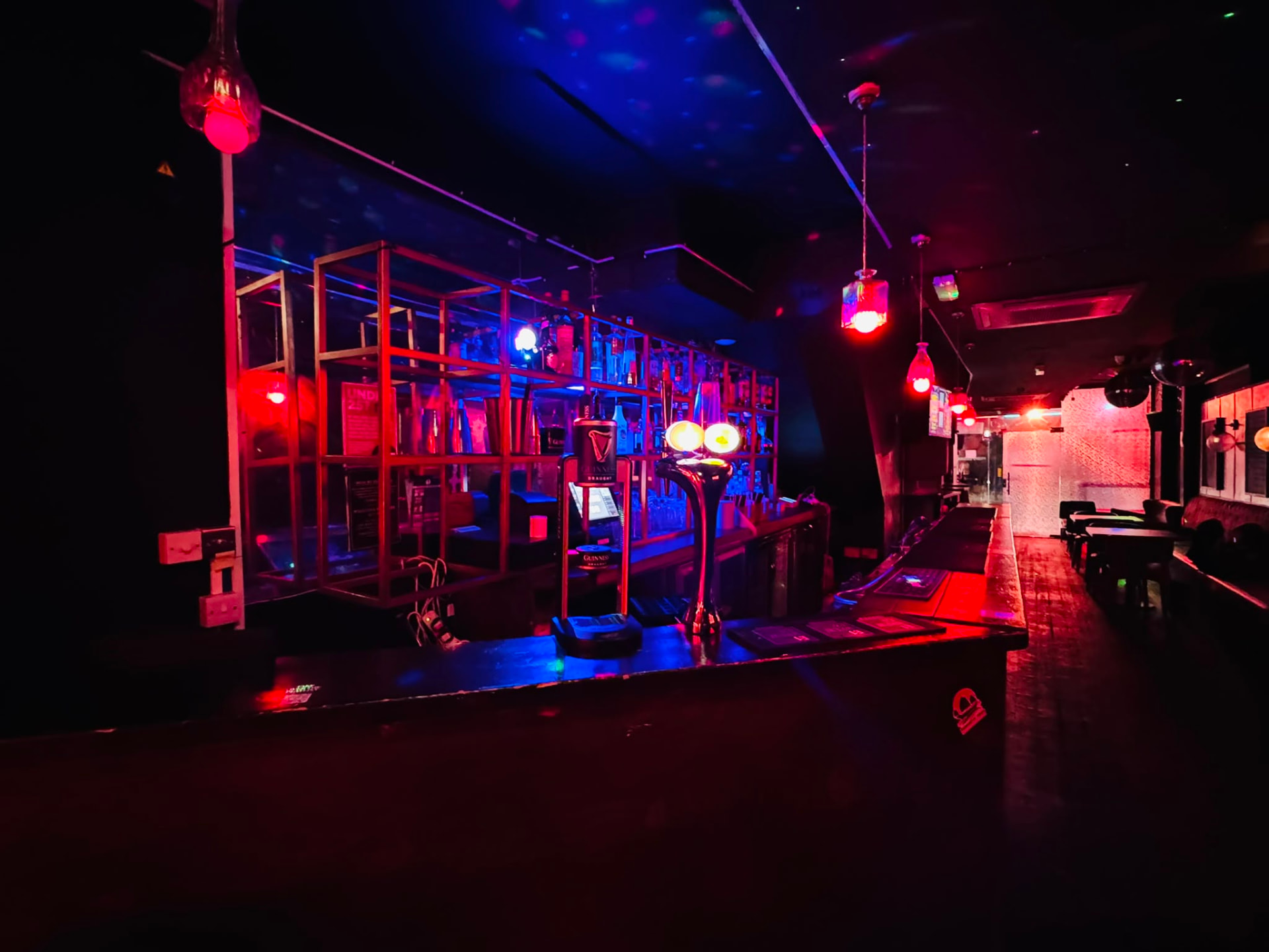 Main bar at 331 Old St lit in red and blue with bottle shelving