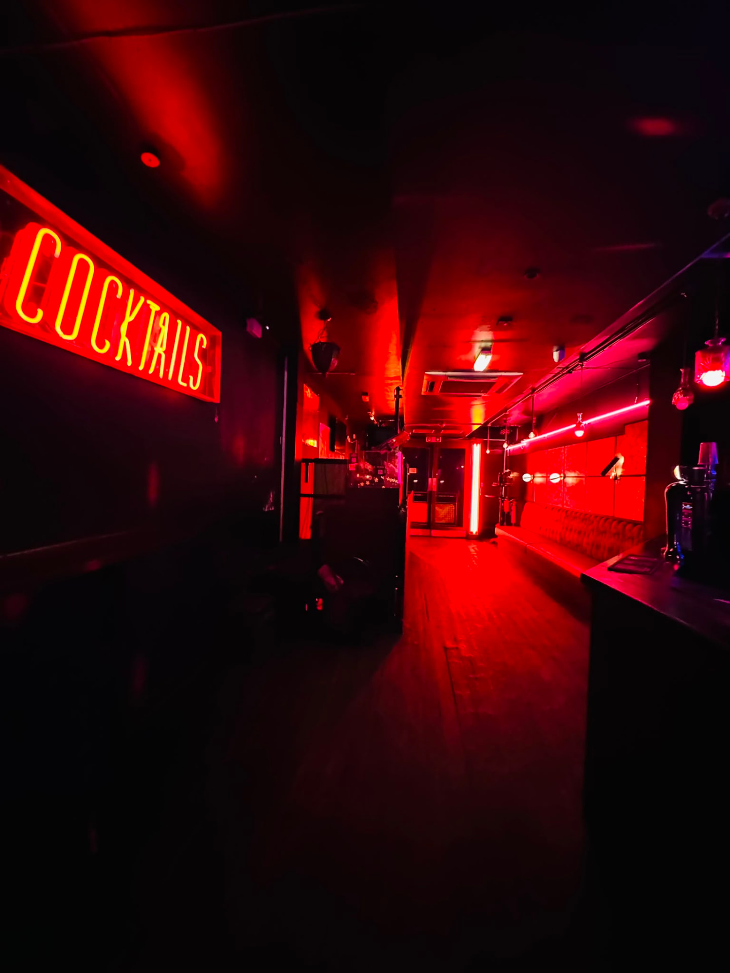 Red-lit retro club interior with velvet booths and a mirrored bar