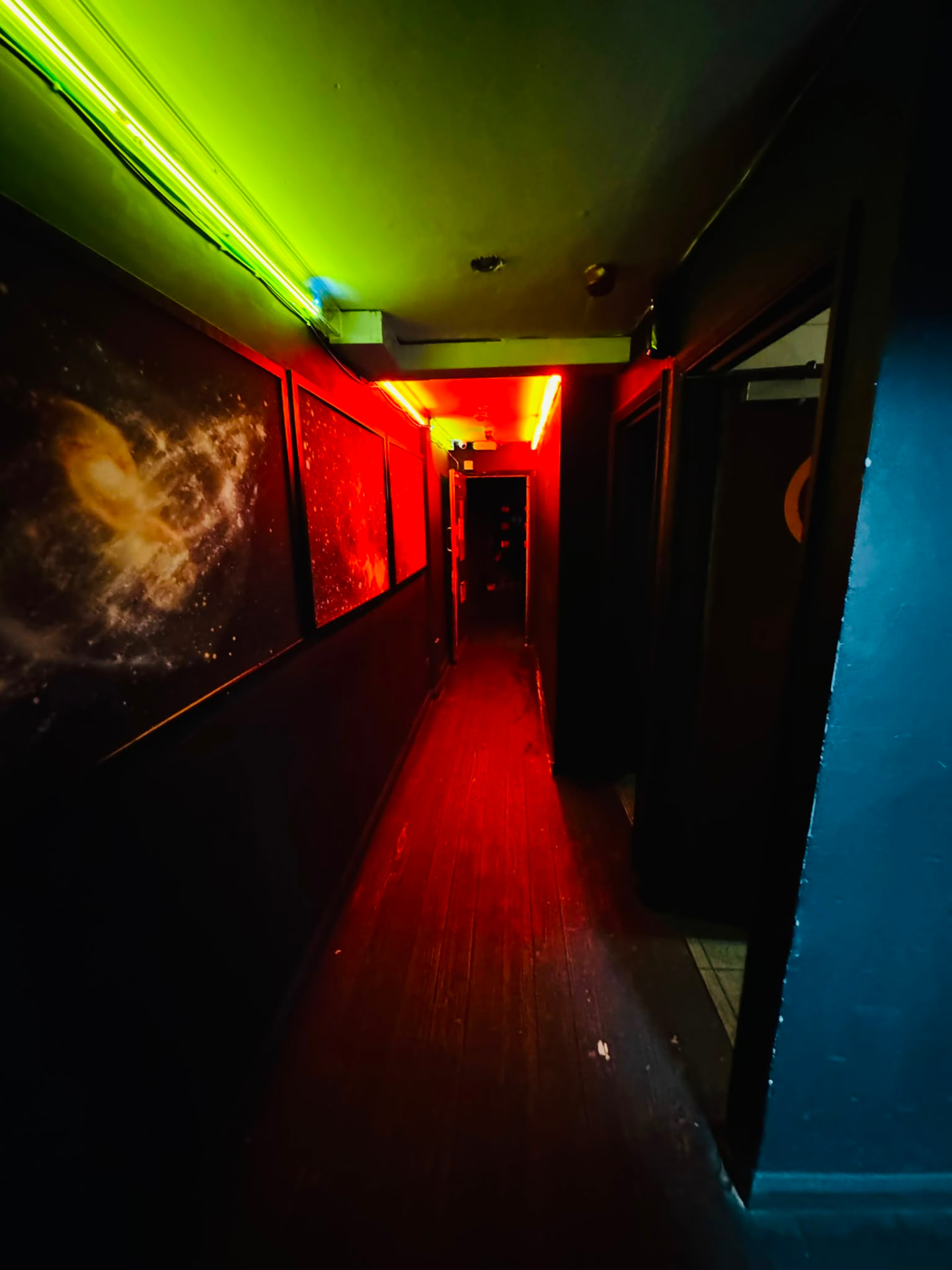 Corridor lit by green and red neon leading deeper into the club